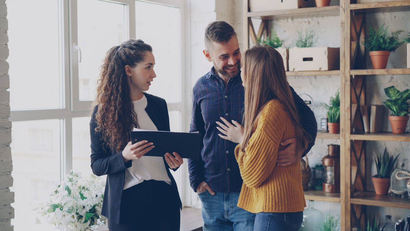 Conseillère présentant un projet à un couple dans un intérieur lumineux